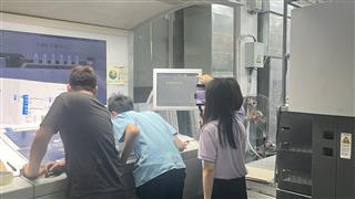 People reviewing sheets beside a printing control monitor