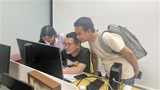 People gathered around a computer in the Holidaypac office