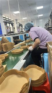 Operator handling a formed rectangular tray beside stacks
