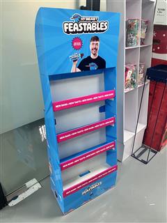 Angled view of the blue Feastables cardboard stand with pink shelf-front graphics
