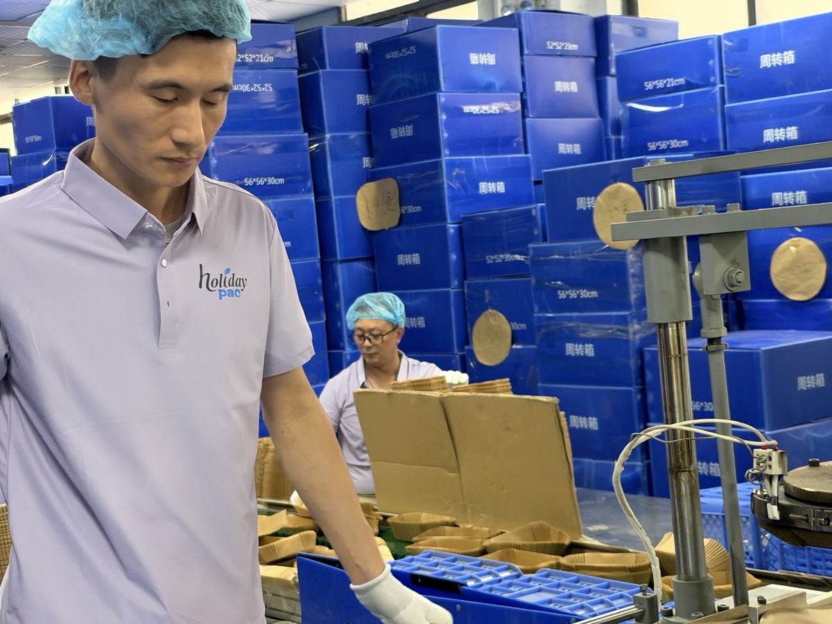Holidaypac workshop operator beside stacks of shaped air fryer paper liners and forming equipment Holidaypac workshop operator beside stacks of shaped air fryer paper liners and forming equipment