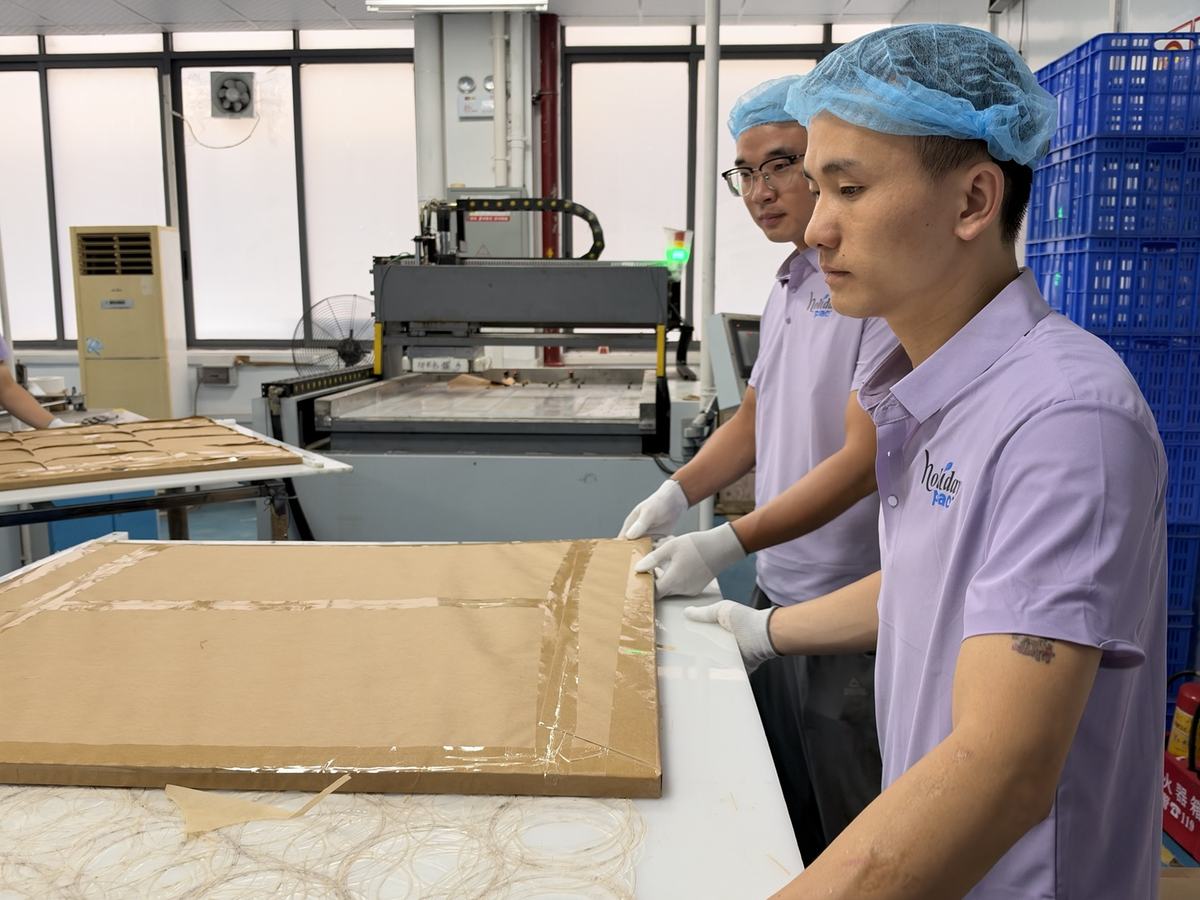 Holidaypac staff checking large brown paper liner blanks on a workshop table Holidaypac staff checking large brown paper liner blanks on a workshop table